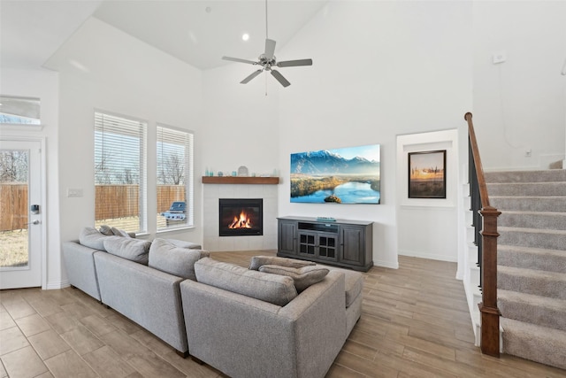 living room featuring wood finished floors, a healthy amount of sunlight, a fireplace, and stairs