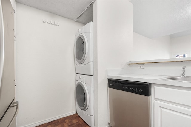 washroom featuring sink, stacked washer and clothes dryer, a textured ceiling, and dark parquet flooring