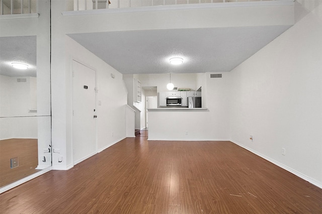 unfurnished living room featuring dark hardwood / wood-style floors and a textured ceiling