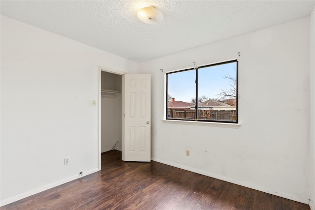 unfurnished bedroom with dark hardwood / wood-style flooring, a closet, and a textured ceiling