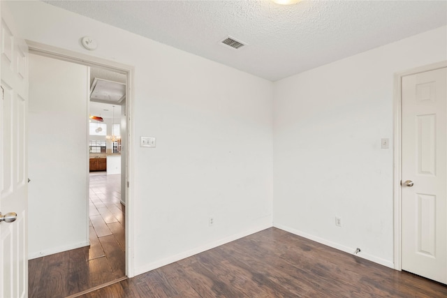 empty room with dark hardwood / wood-style floors and a textured ceiling