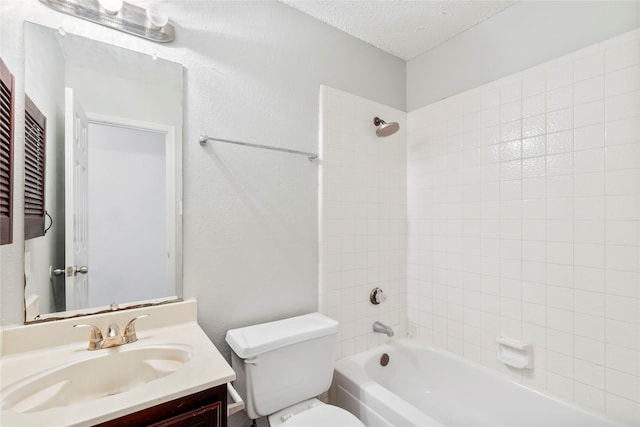 full bathroom featuring vanity, tiled shower / bath combo, toilet, and a textured ceiling