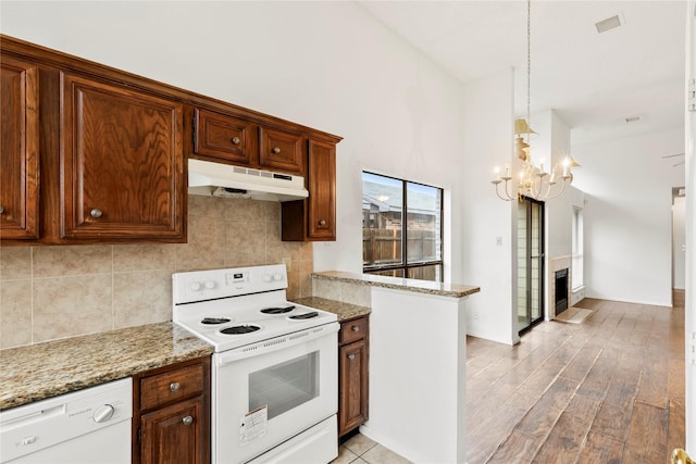 kitchen featuring tasteful backsplash, light hardwood / wood-style flooring, pendant lighting, white appliances, and light stone countertops