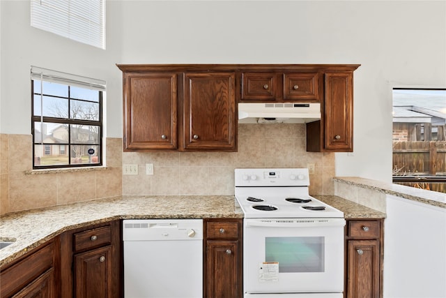 kitchen featuring tasteful backsplash, light stone counters, and white appliances