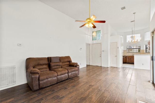 living room with a towering ceiling, dark wood-type flooring, and ceiling fan with notable chandelier