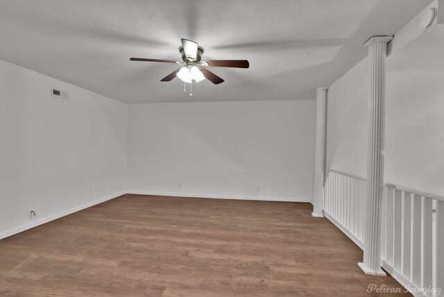 10553 White Oak Dr, Keithville, LA 71047 - empty room featuring hardwood / wood-style flooring, a textured ceiling, ceiling fan, and ornate columns