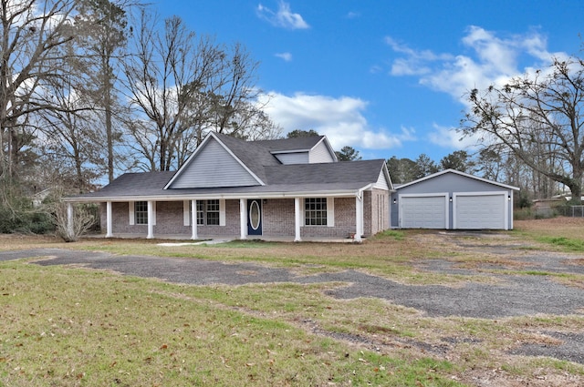 view of front facade with an outbuilding, a garage, a front lawn, and covered porch