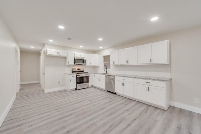 kitchen with light wood-type flooring, appliances with stainless steel finishes, sink, and white cabinets