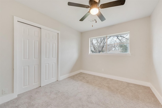 unfurnished bedroom with light colored carpet, ceiling fan, and a closet