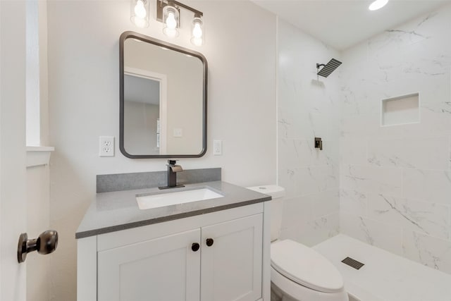 bathroom with vanity, a tile shower, and toilet