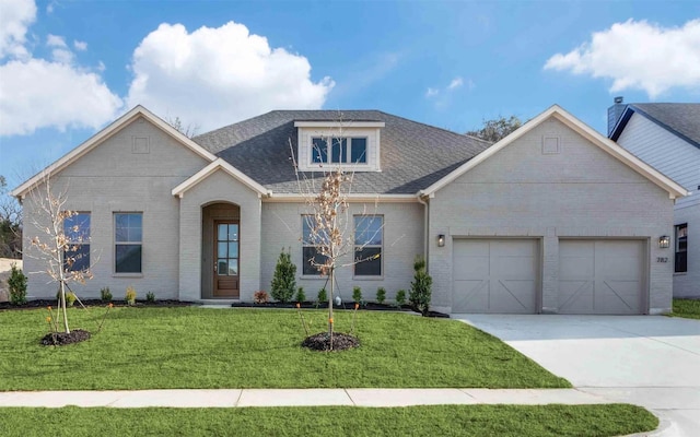 view of front of home with brick siding, a shingled roof, concrete driveway, a front yard, and a garage