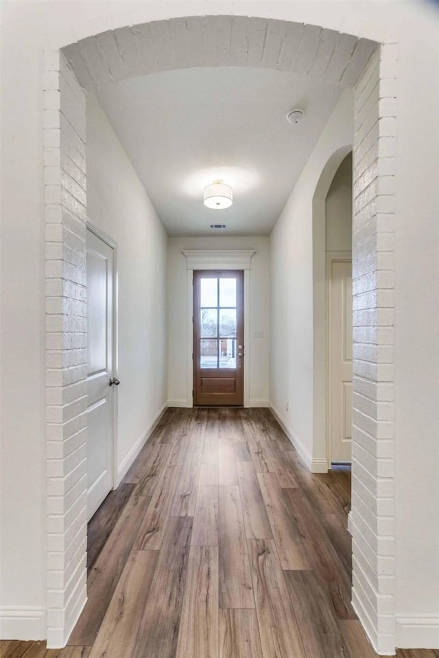 doorway featuring baseboards, arched walkways, and wood finished floors