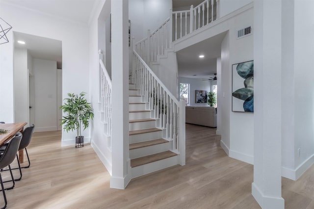 stairs with hardwood / wood-style flooring, a high ceiling, and ceiling fan