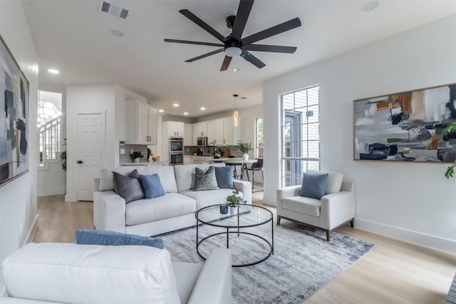 living room with ceiling fan, sink, and light hardwood / wood-style floors