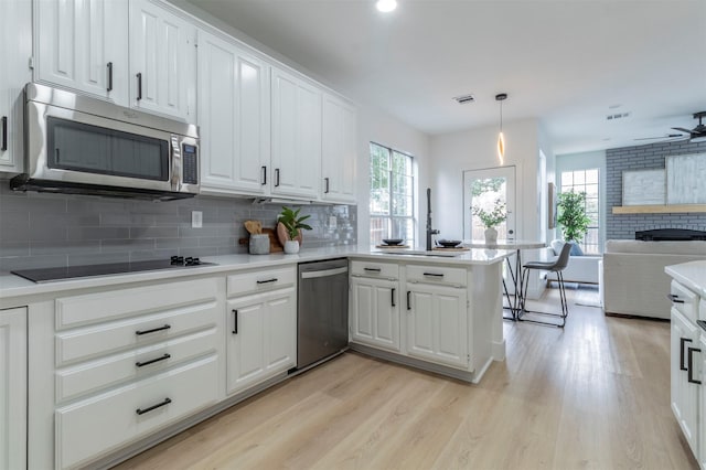 kitchen with white cabinetry, appliances with stainless steel finishes, decorative light fixtures, and kitchen peninsula