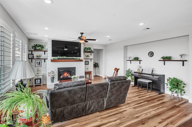 living room featuring a large fireplace, baseboards, visible vents, wood finished floors, and recessed lighting