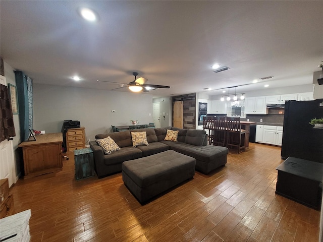 living room featuring hardwood / wood-style floors, a barn door, and ceiling fan