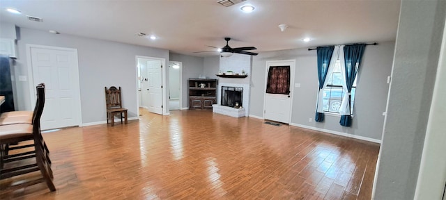 living room featuring hardwood / wood-style flooring, a fireplace, and ceiling fan