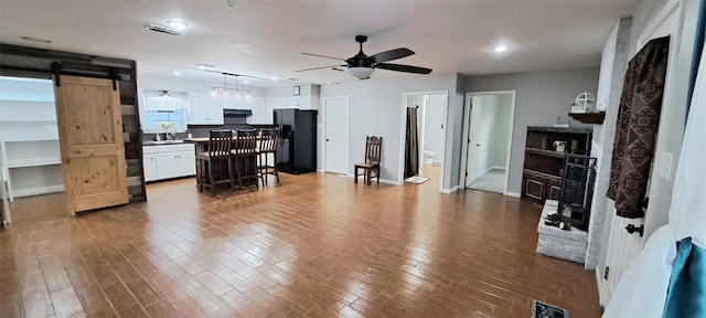 living room with wood-type flooring, a barn door, and ceiling fan