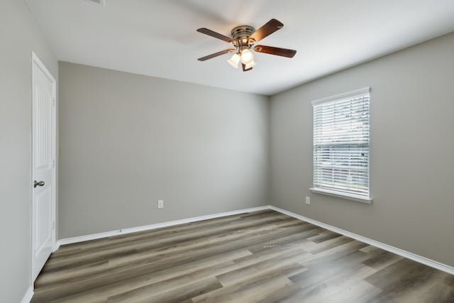 empty room with ceiling fan, dark wood finished floors, and baseboards