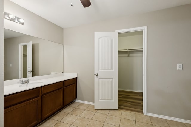 bathroom with vanity, baseboards, a ceiling fan, tile patterned floors, and a walk in closet