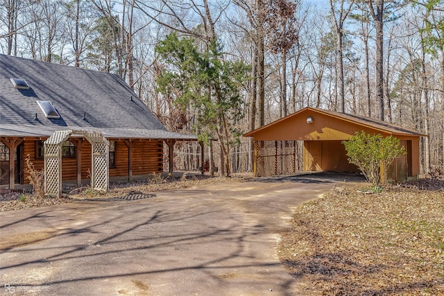 exterior space featuring a carport, roof with shingles, driveway, and log siding