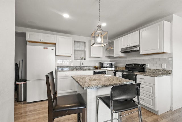 kitchen featuring stone counters, pendant lighting, white cabinets, a center island, and black appliances