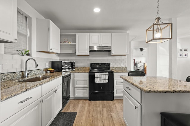 kitchen featuring pendant lighting, sink, white cabinets, light stone counters, and black appliances