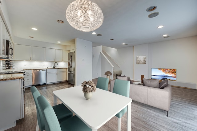 dining space featuring sink, a chandelier, and light hardwood / wood-style flooring