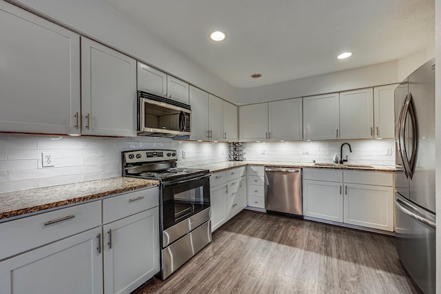 2722 Knight St Unit 316C, Dallas, TX 75219 - kitchen featuring stainless steel appliances, a sink, dark wood-type flooring, tasteful backsplash, and light stone countertops