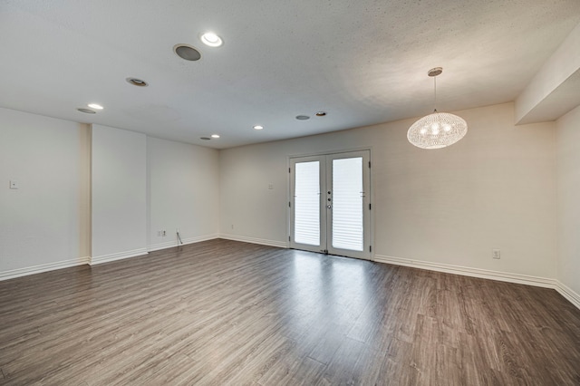 empty room with french doors, hardwood / wood-style floors, a textured ceiling, and a notable chandelier