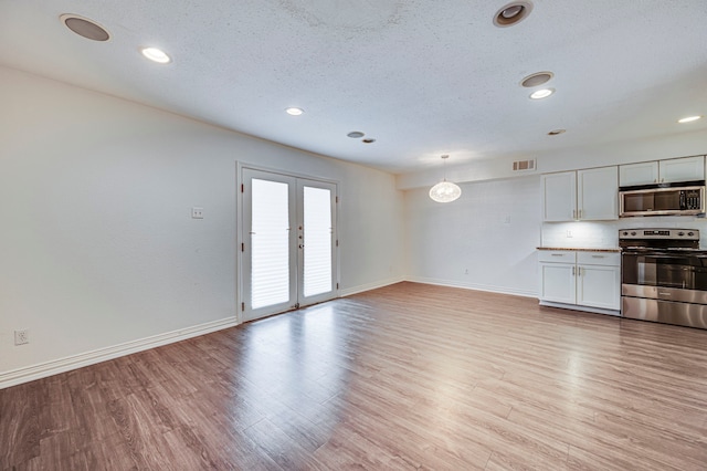 unfurnished living room featuring french doors, a textured ceiling, and light wood-type flooring