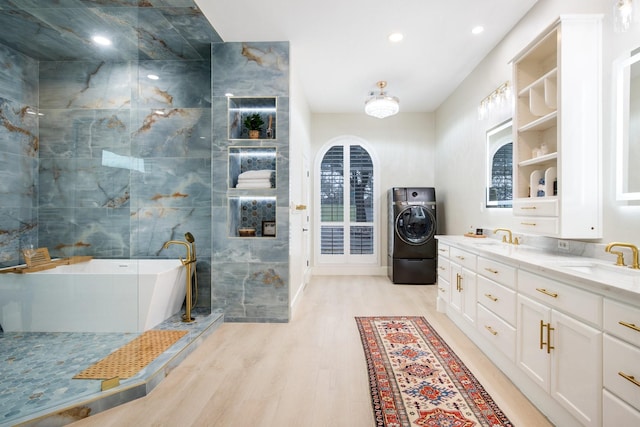 bathroom featuring washer / dryer, vanity, a bath, plenty of natural light, and hardwood / wood-style floors