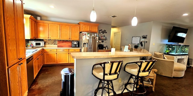 kitchen featuring pendant lighting, decorative backsplash, stainless steel appliances, and a kitchen bar