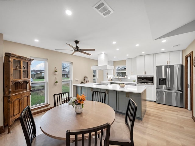 dining space with sink, light hardwood / wood-style floors, and ceiling fan