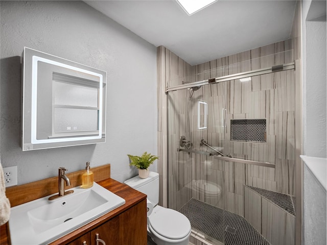 bathroom with vanity, a shower with shower door, and toilet