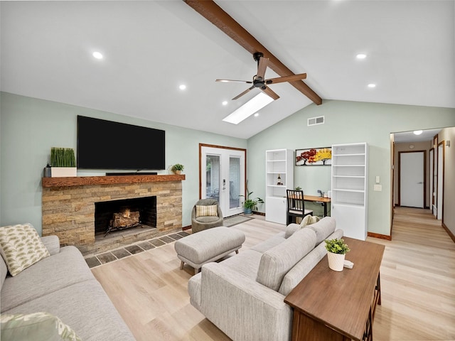 living room featuring lofted ceiling with beams, ceiling fan, a fireplace, and light hardwood / wood-style flooring