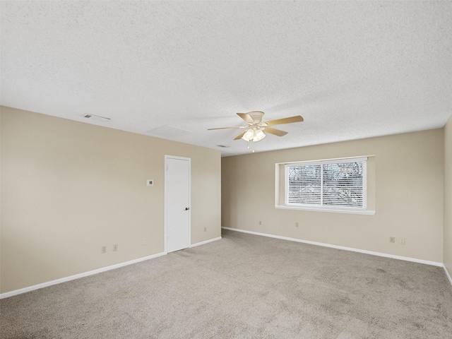 empty room with ceiling fan, light colored carpet, and a textured ceiling