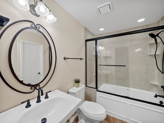 full bathroom with sink, shower / bath combination with glass door, and toilet