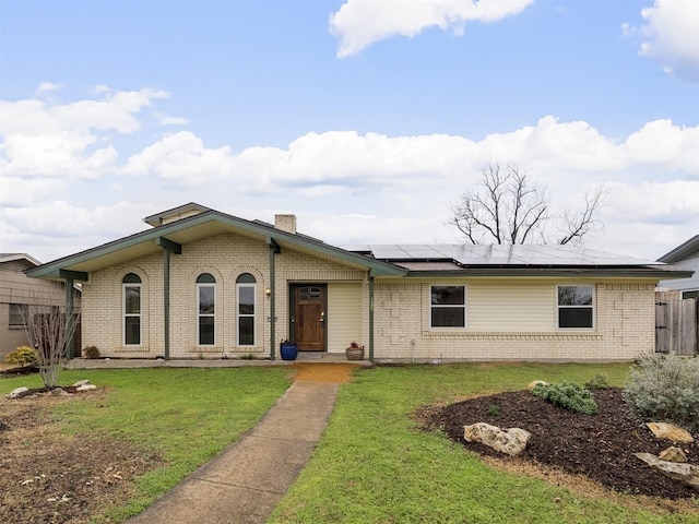 ranch-style house featuring a front lawn and solar panels