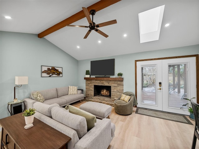 living room featuring ceiling fan, vaulted ceiling with beams, a fireplace, french doors, and light wood-type flooring