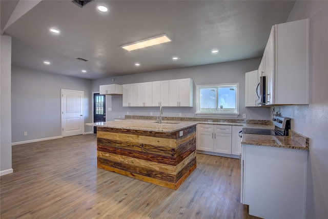4340 Fm 1563, Wolfe City, TX 75496 - kitchen featuring light wood-style flooring, dark stone countertops, a sink, white cabinets, and appliances with stainless steel finishes