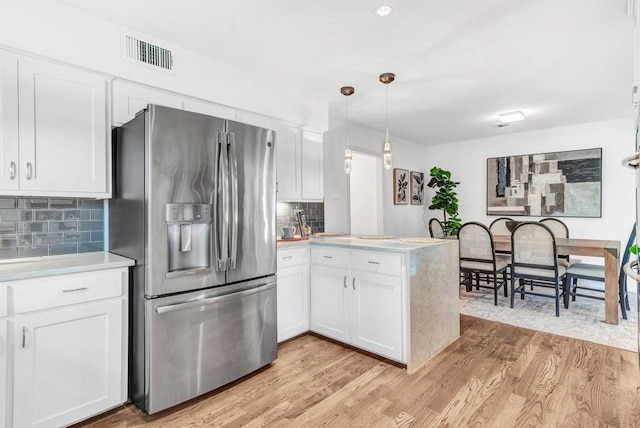 kitchen featuring stainless steel fridge with ice dispenser, decorative light fixtures, white cabinets, kitchen peninsula, and light hardwood / wood-style flooring