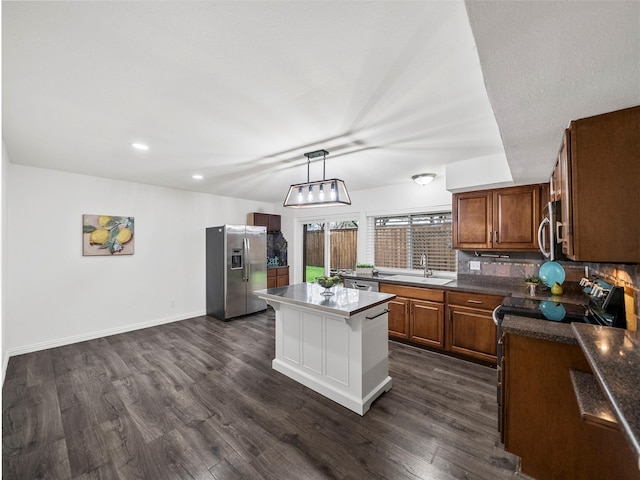 kitchen with stainless steel appliances, dark wood-type flooring, a center island, brown cabinets, and tasteful backsplash