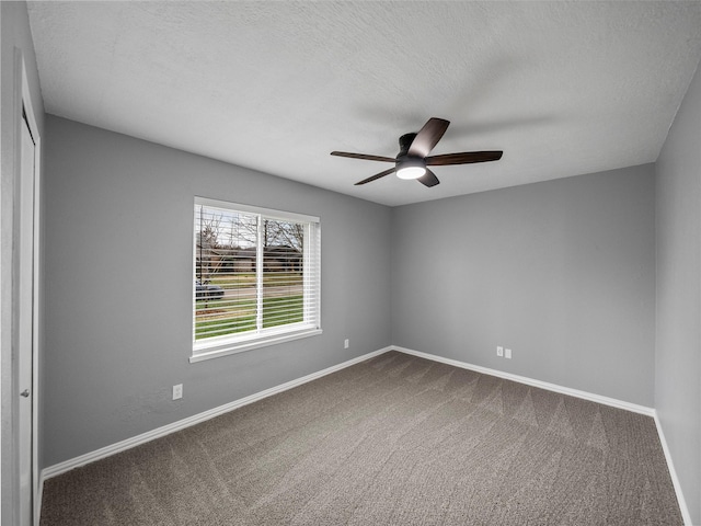 carpeted spare room featuring a textured ceiling, ceiling fan, and baseboards