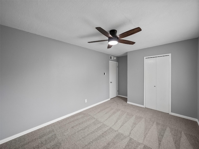 unfurnished bedroom with a textured ceiling, carpet floors, visible vents, baseboards, and a closet