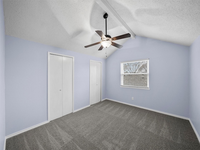 unfurnished bedroom featuring vaulted ceiling with beams, ceiling fan, a textured ceiling, baseboards, and dark carpet