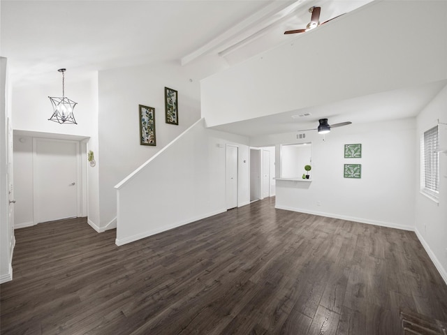 unfurnished living room featuring ceiling fan with notable chandelier, beamed ceiling, dark wood-style flooring, and baseboards