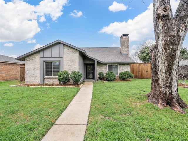 mid-century modern home with a front yard, brick siding, fence, and a chimney