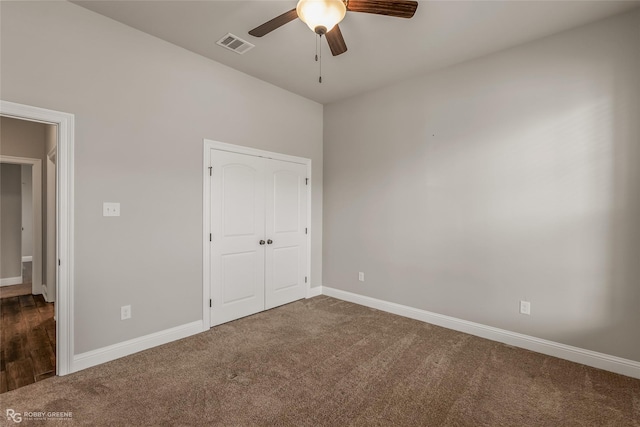 unfurnished bedroom with ceiling fan, dark carpet, and a closet